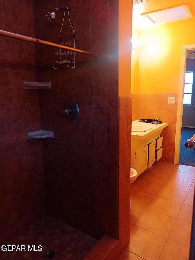 bathroom with tile patterned flooring, toilet, and a tile shower