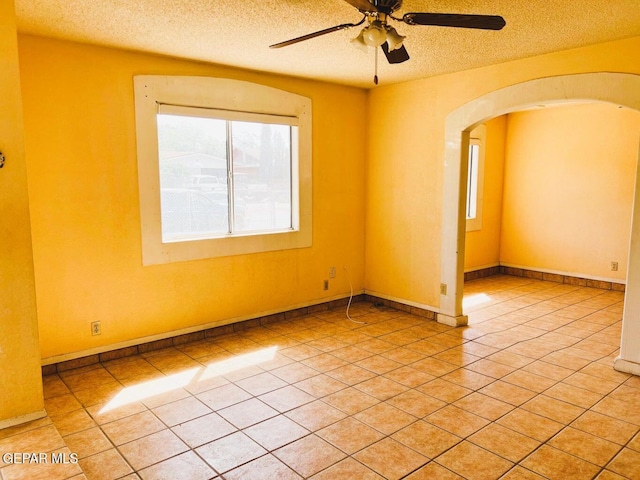 unfurnished room with light tile patterned flooring, ceiling fan, and a textured ceiling