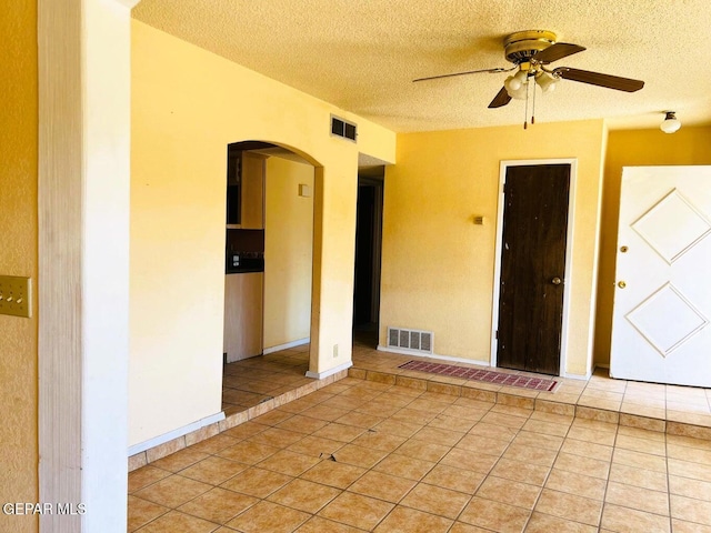 tiled empty room featuring ceiling fan and a textured ceiling