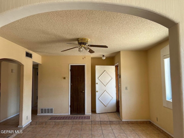 interior space featuring ceiling fan, plenty of natural light, and a textured ceiling