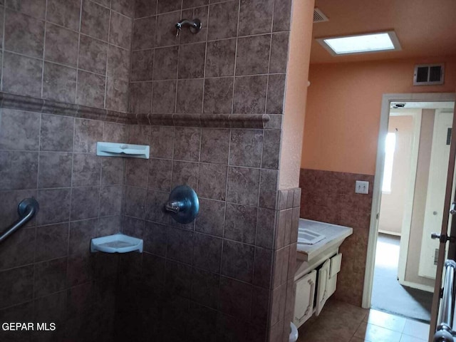 bathroom with tile patterned flooring, vanity, and a tile shower