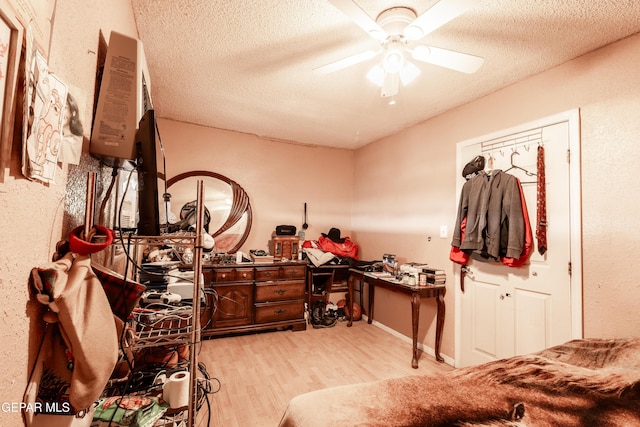 bedroom with ceiling fan, light hardwood / wood-style flooring, and a textured ceiling