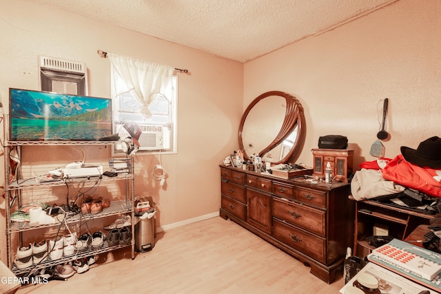 interior space featuring cooling unit, light hardwood / wood-style flooring, and a textured ceiling