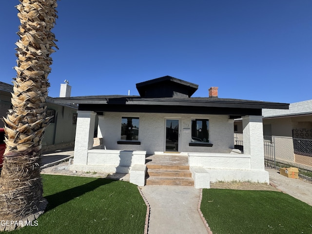 view of front of home featuring fence, a chimney, stucco siding, and a porch