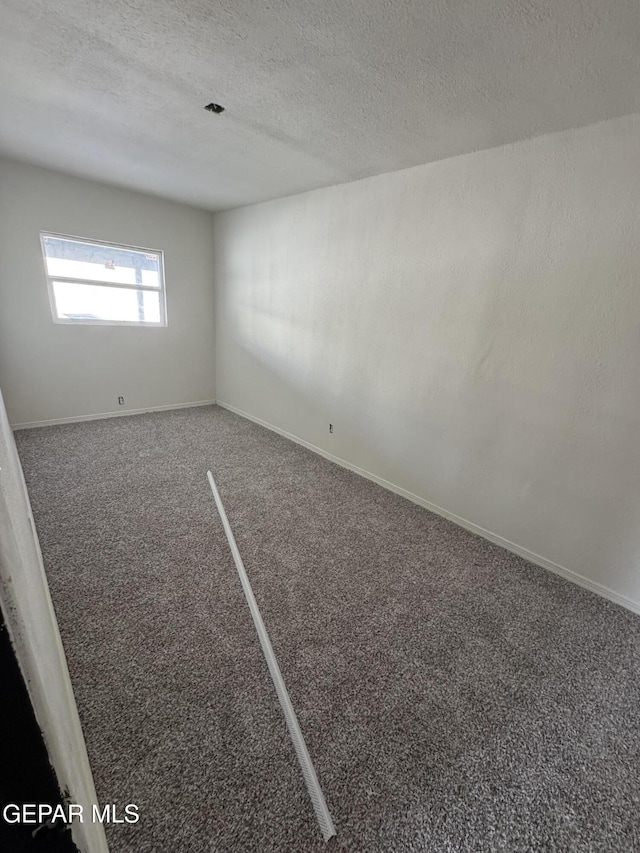 empty room with dark colored carpet and a textured ceiling