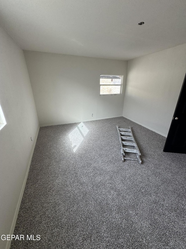 unfurnished room with dark colored carpet