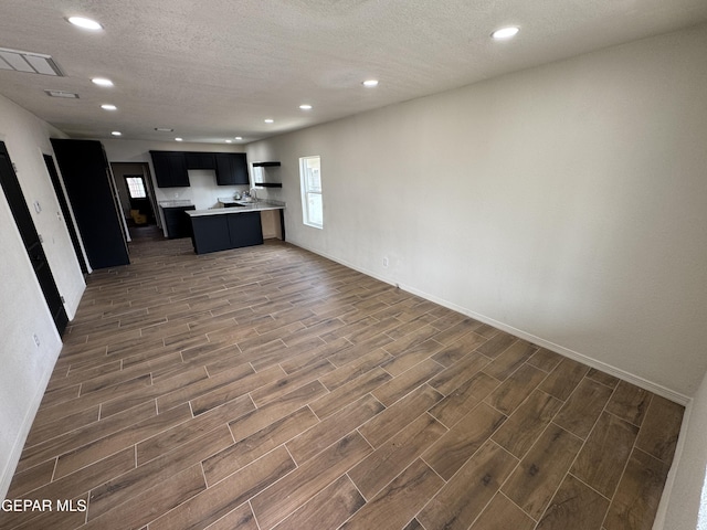 kitchen with open floor plan, wood finish floors, light countertops, and a textured ceiling