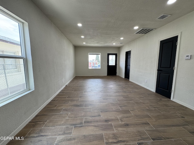 spare room with a textured wall, visible vents, wood finish floors, and recessed lighting