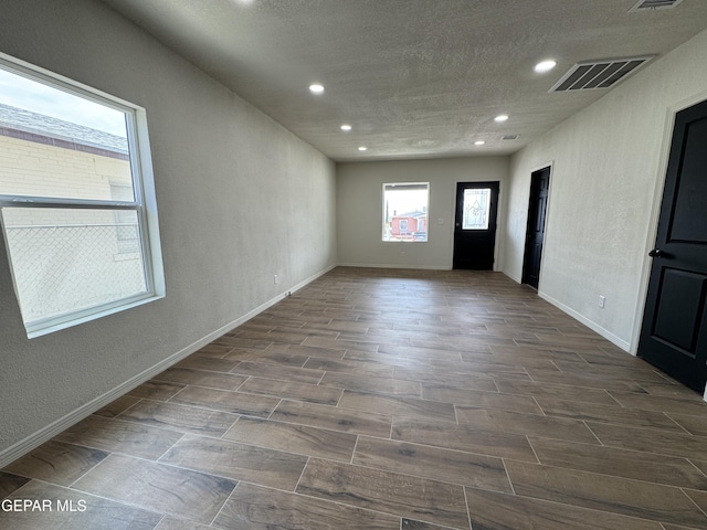 unfurnished room with visible vents, a textured wall, recessed lighting, and wood finish floors