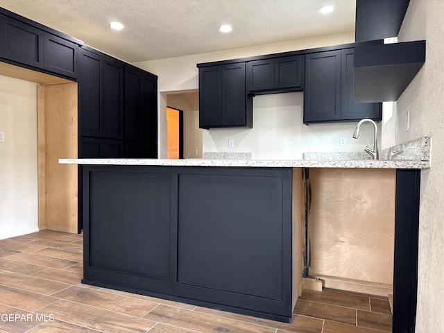 kitchen with wood tiled floor, light stone countertops, recessed lighting, and a textured ceiling