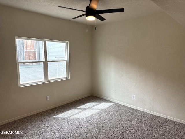 carpeted empty room featuring baseboards, ceiling fan, a textured wall, and a textured ceiling