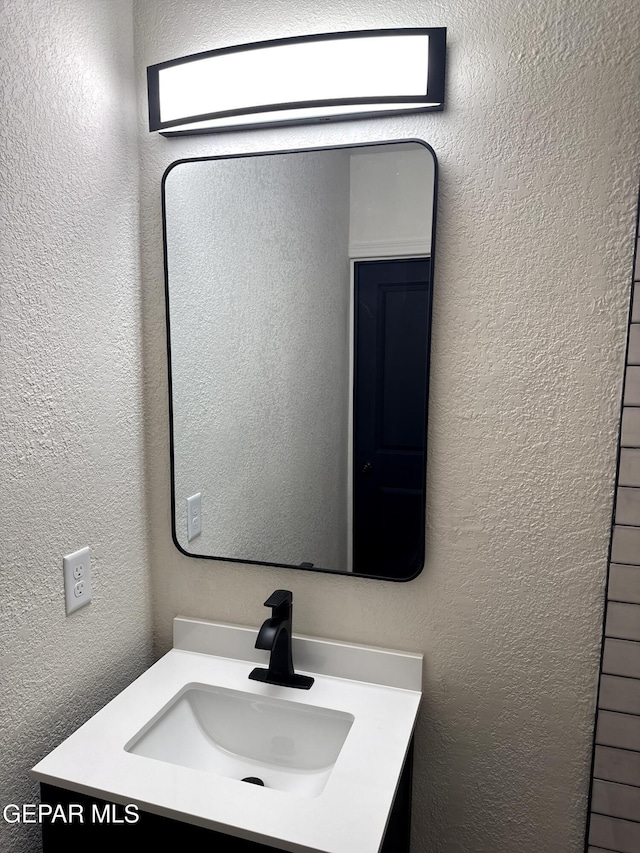bathroom featuring vanity and a textured wall