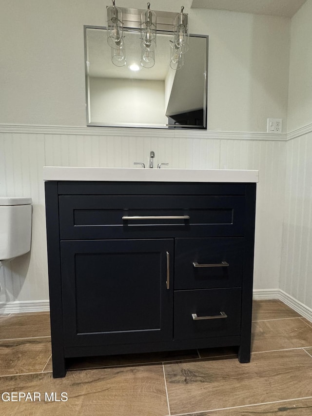 interior details with a sink, wood finished floors, and wainscoting