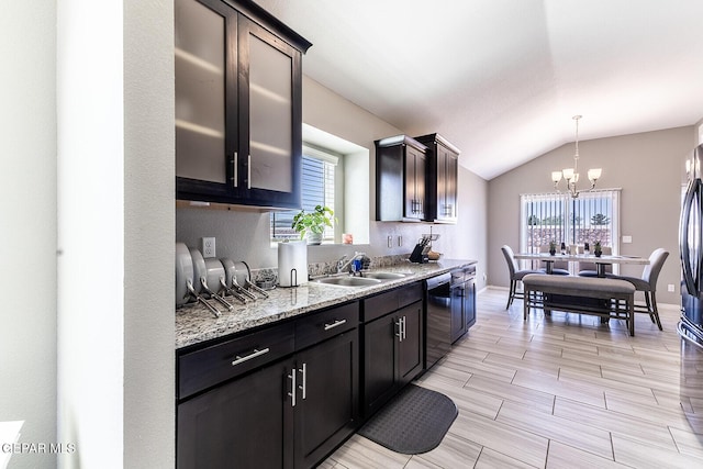 kitchen featuring vaulted ceiling, dishwasher, sink, hanging light fixtures, and light stone countertops