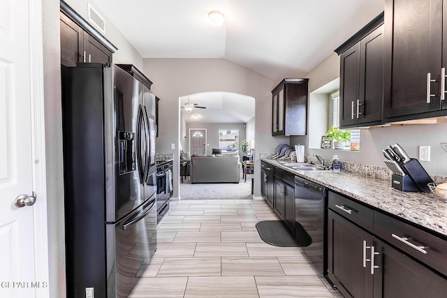 kitchen featuring vaulted ceiling, dark brown cabinets, black dishwasher, and stainless steel fridge