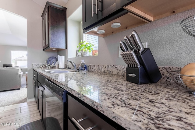 kitchen with sink, dark brown cabinets, light stone countertops, and dishwasher