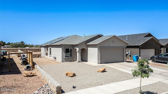 ranch-style house with a garage and solar panels