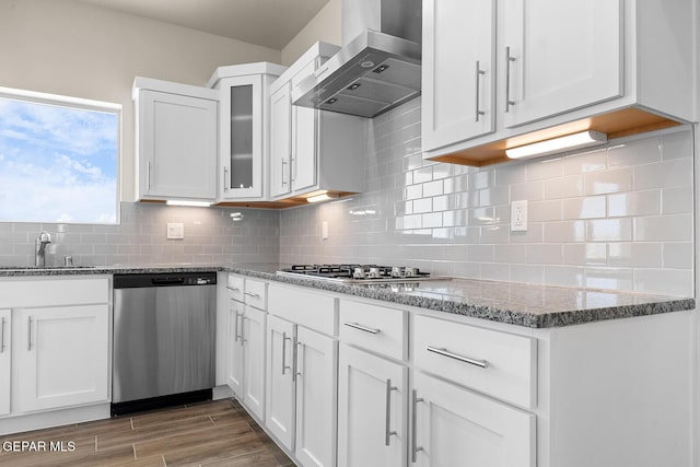 kitchen with wall chimney exhaust hood, sink, light stone counters, appliances with stainless steel finishes, and white cabinets