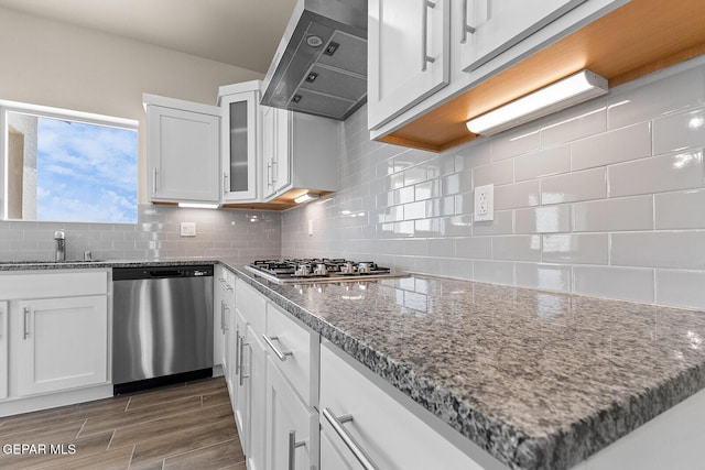 kitchen with white cabinetry, appliances with stainless steel finishes, backsplash, and wall chimney range hood