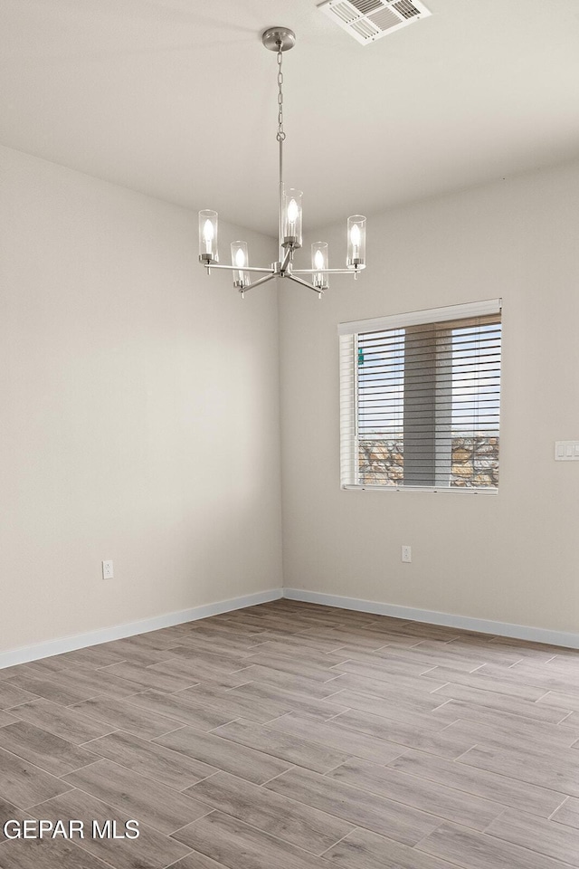 unfurnished room with hardwood / wood-style floors and a chandelier