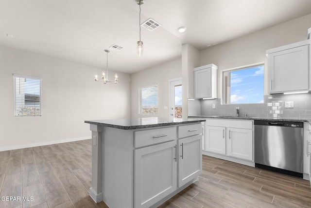 kitchen featuring a center island, stainless steel dishwasher, pendant lighting, decorative backsplash, and white cabinets