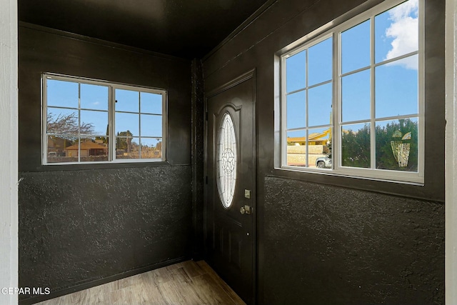 foyer with crown molding, plenty of natural light, and hardwood / wood-style floors