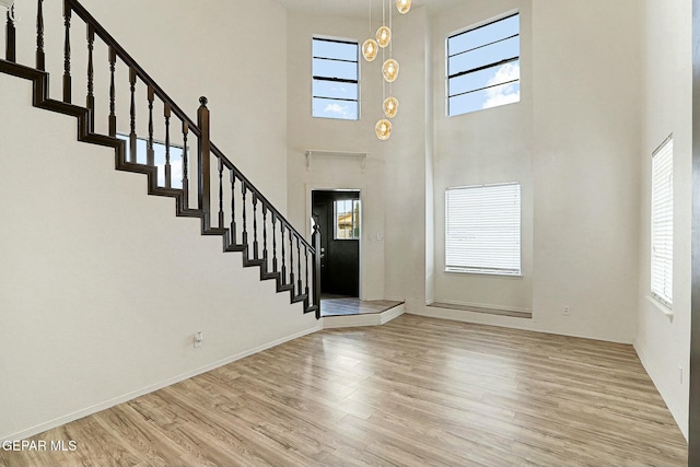 foyer featuring a towering ceiling, a wealth of natural light, and light hardwood / wood-style floors