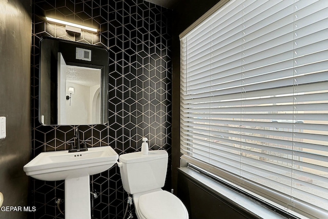 bathroom featuring toilet and tile walls