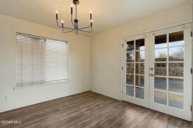 unfurnished dining area featuring a healthy amount of sunlight, hardwood / wood-style flooring, french doors, and a chandelier