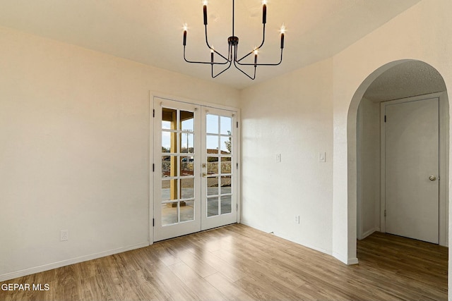 unfurnished dining area featuring french doors, a chandelier, and light wood-type flooring