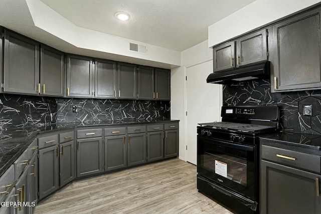 kitchen featuring tasteful backsplash, dark stone counters, black range with gas cooktop, and light hardwood / wood-style flooring