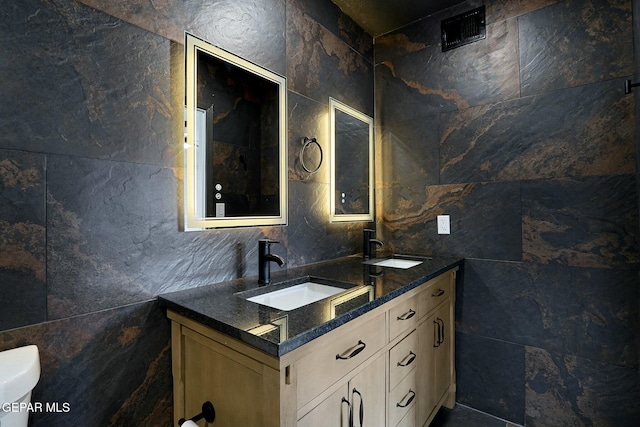 bathroom with vanity, toilet, and tile walls