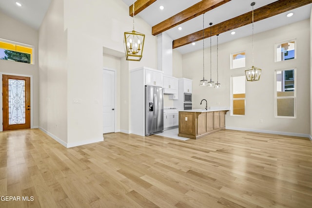 kitchen with hanging light fixtures, a kitchen island with sink, a chandelier, and stainless steel appliances