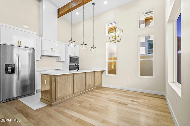 kitchen with white cabinetry, stainless steel appliances, a center island, a high ceiling, and decorative light fixtures