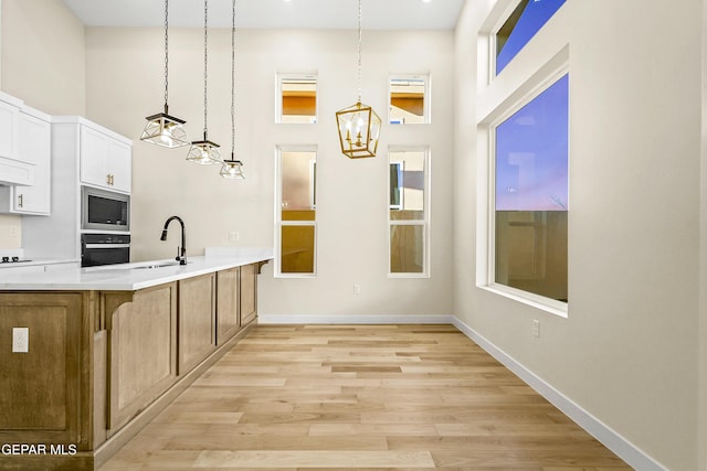 kitchen featuring hanging light fixtures, sink, stainless steel microwave, and wall oven