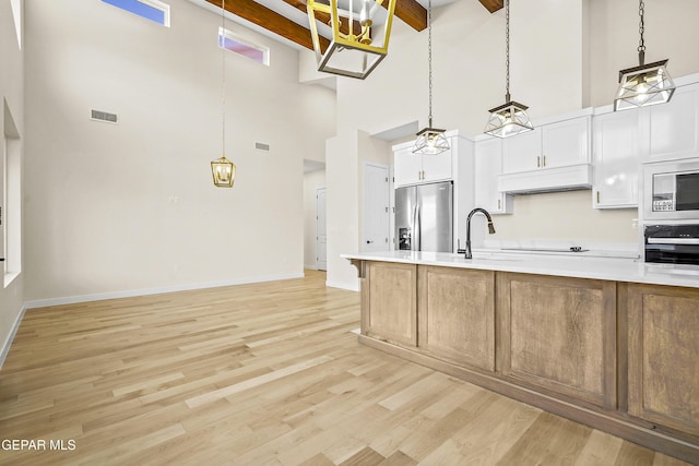 kitchen with white cabinetry, stainless steel refrigerator with ice dispenser, light hardwood / wood-style floors, built in microwave, and oven