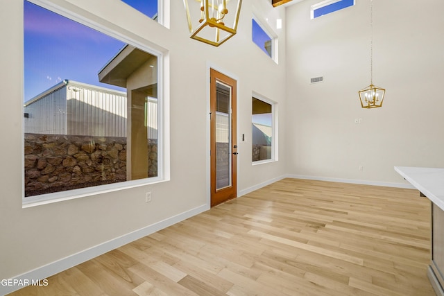 entryway with a notable chandelier, a high ceiling, and light wood-type flooring