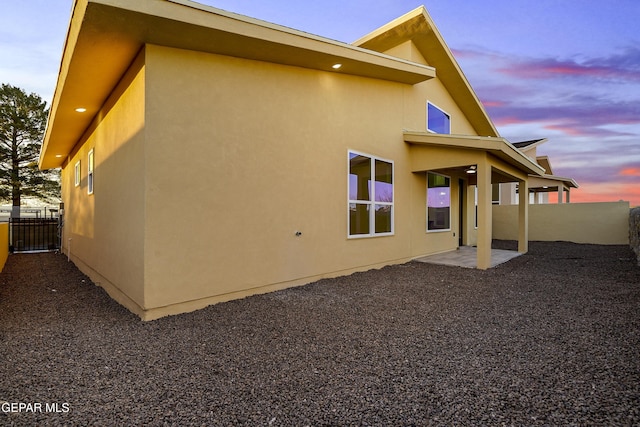 back house at dusk featuring a patio