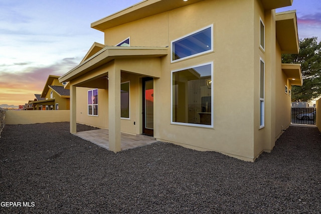 back house at dusk featuring a patio area