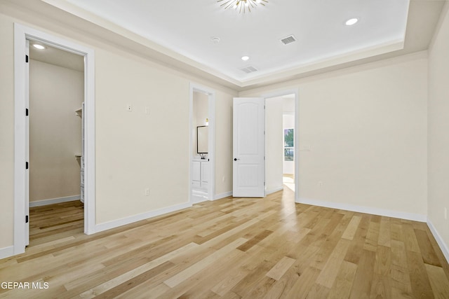 unfurnished room featuring a tray ceiling and light wood-type flooring