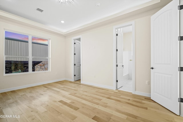 unfurnished bedroom with ensuite bath and light hardwood / wood-style floors