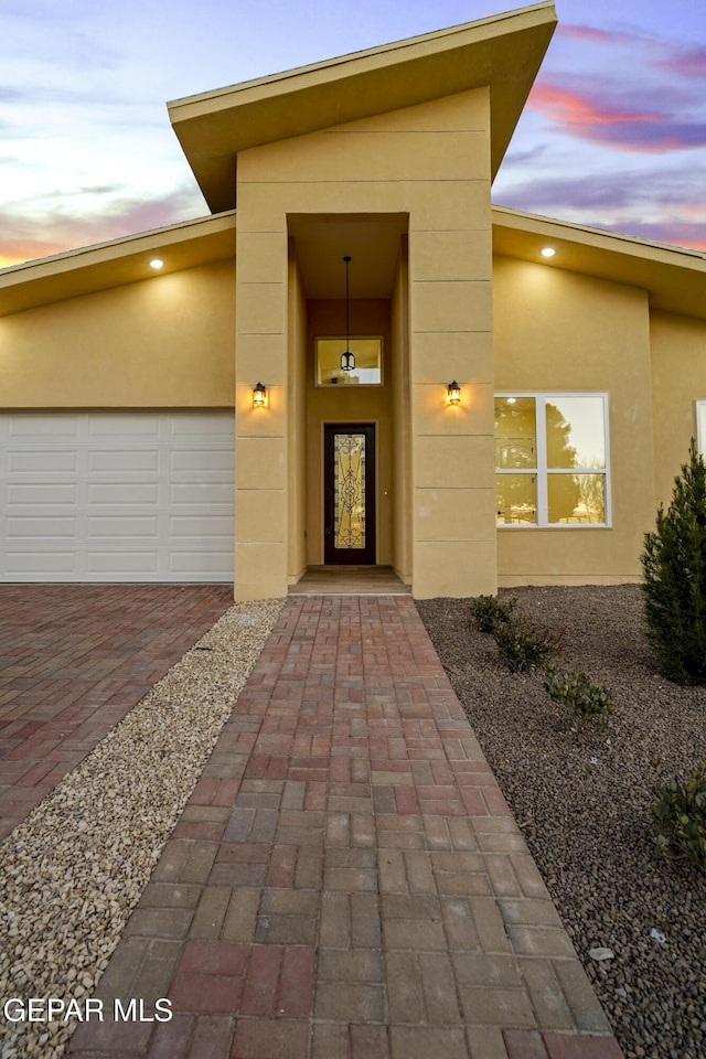 exterior entry at dusk featuring a garage