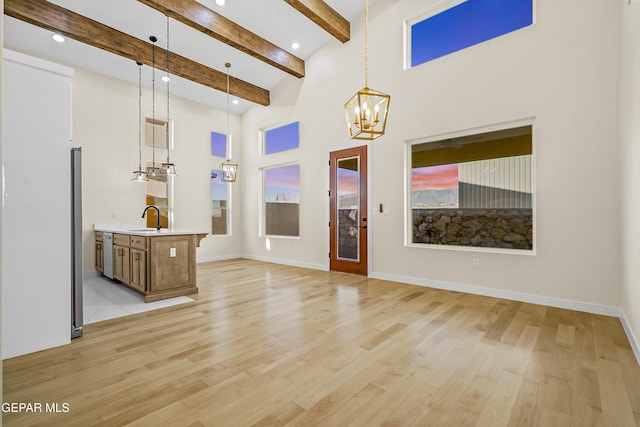 entrance foyer with a high ceiling, sink, light hardwood / wood-style floors, and beam ceiling