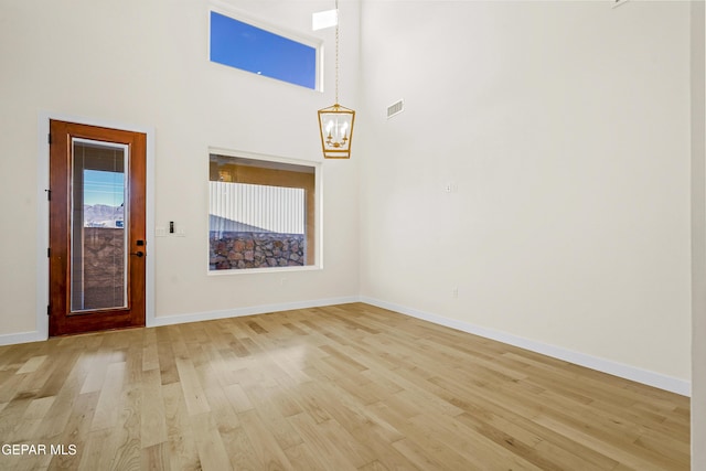 entryway with a chandelier, light hardwood / wood-style floors, and a high ceiling