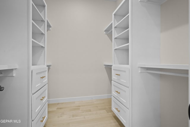 walk in closet with light hardwood / wood-style flooring