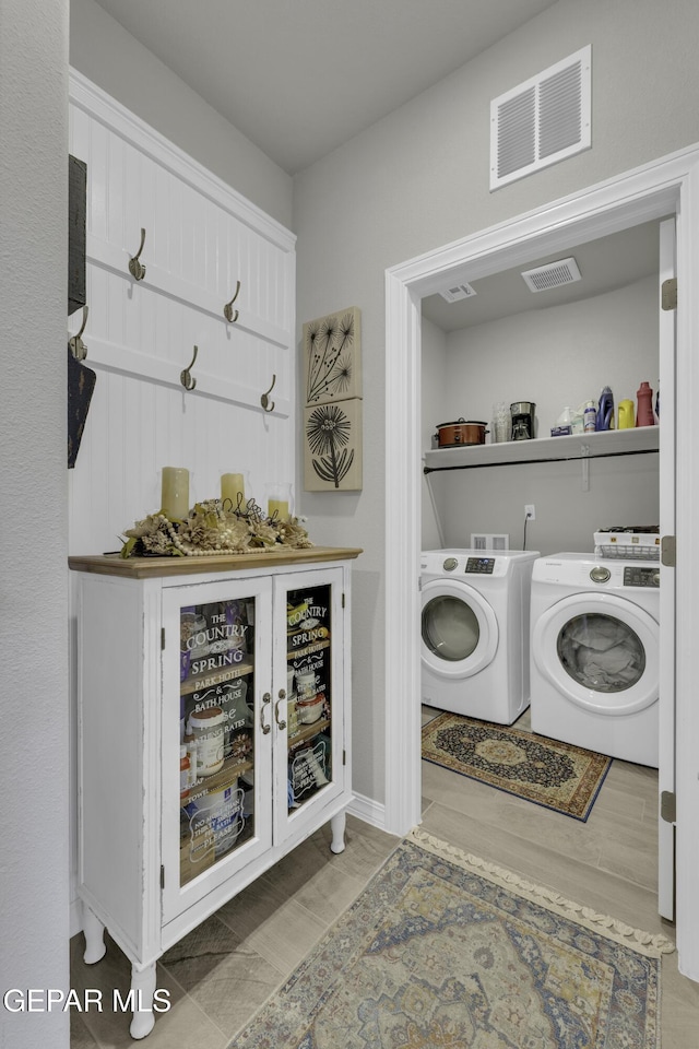 laundry area with separate washer and dryer and light hardwood / wood-style floors