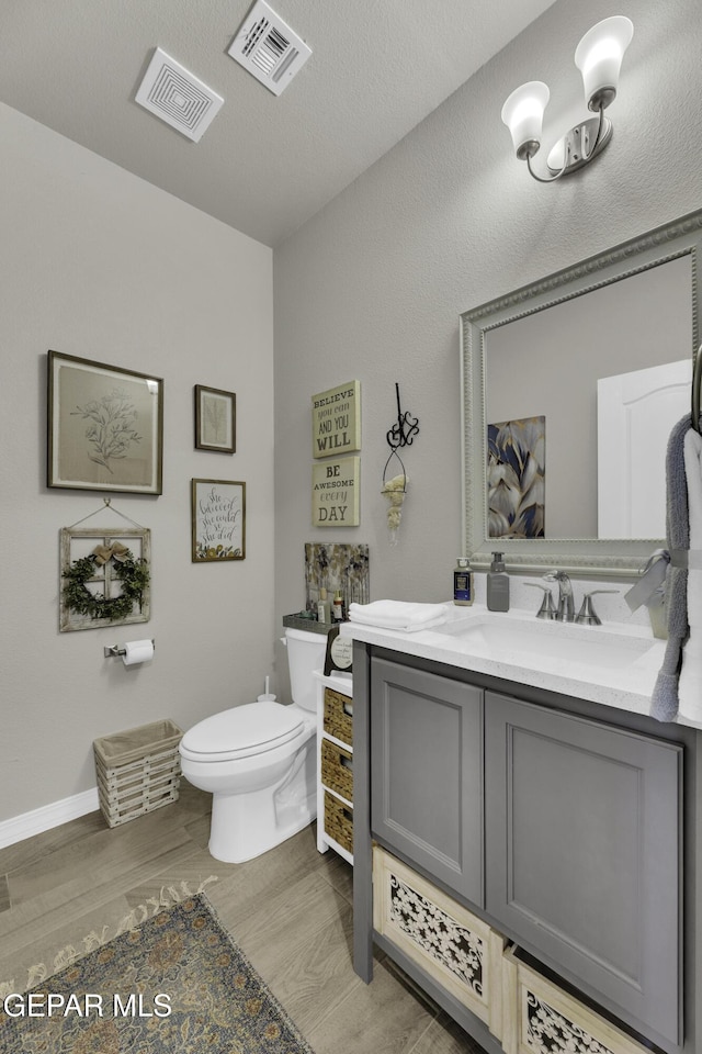 bathroom featuring vanity, hardwood / wood-style flooring, a textured ceiling, and toilet