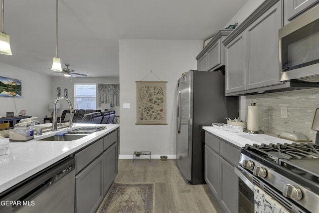 kitchen with sink, gray cabinets, stainless steel appliances, decorative backsplash, and decorative light fixtures