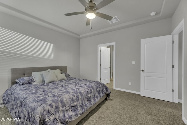 carpeted bedroom with a tray ceiling and ceiling fan