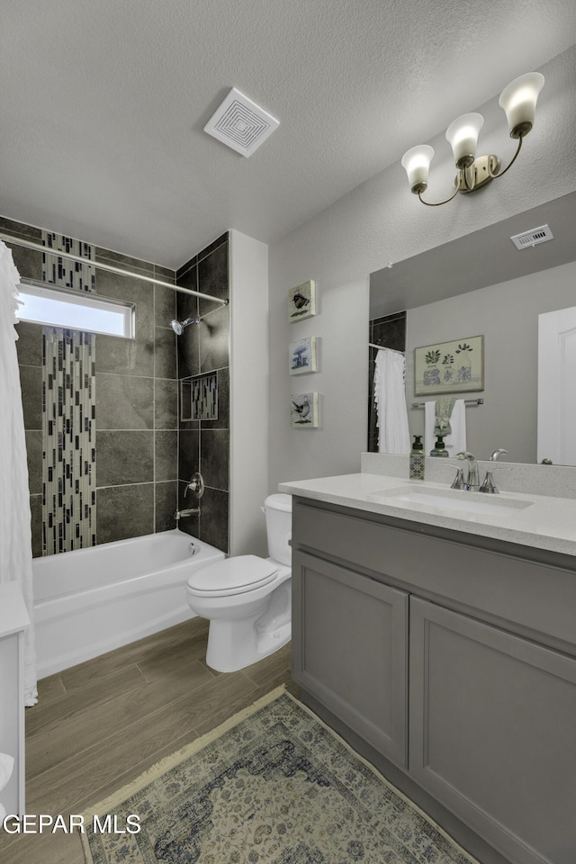 full bathroom with toilet, a textured ceiling, vanity, shower / bath combo with shower curtain, and hardwood / wood-style flooring